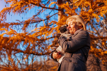 Master walking pug dog in autumn park. Happy woman hugging pet.