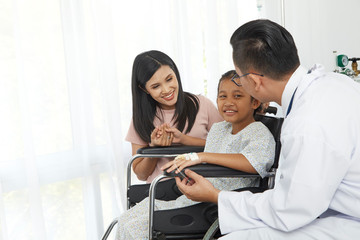 Asian male doctor talking to young child wheelchair and mother, Concept hospital care