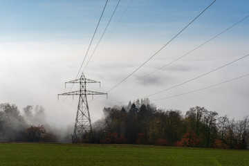 Elektrische Leitung am berg in den nebel in das Tal