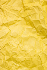 A crumpled yellow sheet of paper. Vertical background.