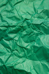 A crumpled green sheet of paper. Vertical background.
