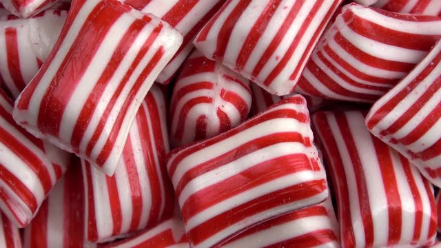 Red and white Christmas striped rounded rectangle peppermint candies spinning video close up