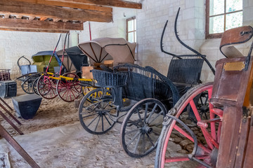 Fototapeta na wymiar Vintage carriages on display in the stable of medieval castle in France.