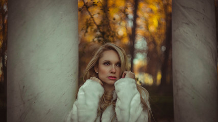 melancholy falling, scene of autumn and winter, beautiful blond woman with gestures of melancholy dressed in grey coat
