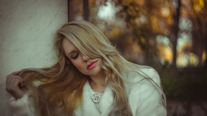 melancholy falling, scene of autumn and winter, beautiful blond woman with gestures of melancholy dressed in grey coat