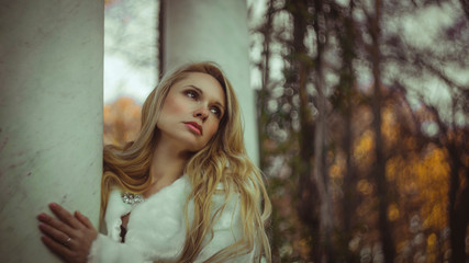 Naklejka premium melancholy falling, scene of autumn and winter, beautiful blond woman with gestures of melancholy dressed in grey coat