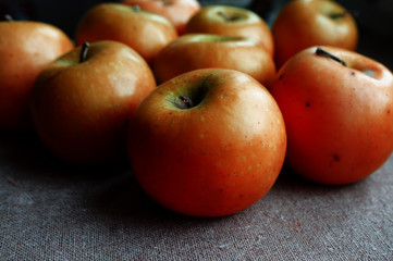 Orange apples, contrasting dark background.