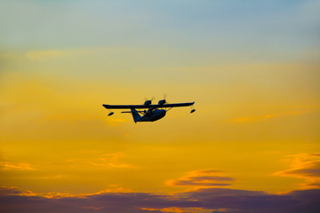 Fototapeta na wymiar Seaplane with two propellers on the wings against the sky at sunset.