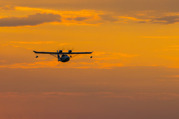 Seaplane with two propellers on the wings against the sky at sunset.