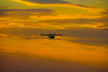 Fototapeta na wymiar Seaplane with two propellers on the wings against the sky at sunset.