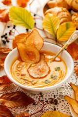 Pumpkin soup with the addition of pear chips in a white ceramic bowl. Delicious and healthy vegan soup