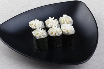Sushi Maki on a black plate. Triangular black plate with sushi on a light background.