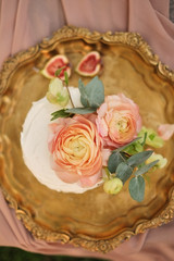 pink cake decorated with ranunculus flowers on a golden tray