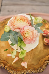 pink cake decorated with ranunculus flowers on a golden tray