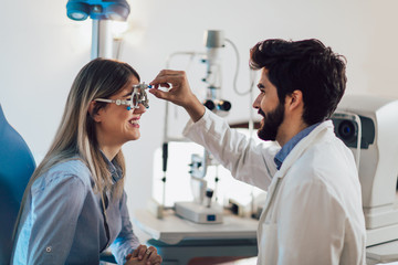 Optometrist checking patient eyesight and vision correction - obrazy, fototapety, plakaty
