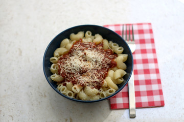 Bowl of pasta with tomato sauce and grated parmesan cheese. Selective focus.