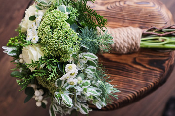 A bridal bouquet of white and green flowers stands on a chair against a wooden floor.