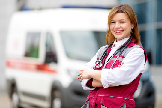 Medical concept. Happy paramedic female with phonendoscope at emergency car background