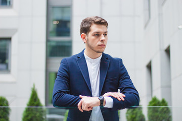 Young businessman in a blue jacket. On the left hand watch