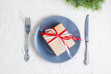 Christmas table setting with grey plate, gift box and silverware on light background, Fir tree branch