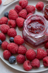 Raspberry jam in jar with raspberry and blueberry near