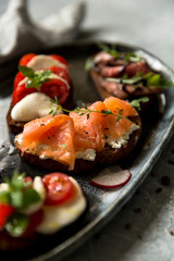 Sandwiches with roast beef and arugula, salmon and cumin, mozzarella and tomatoes on brown bread