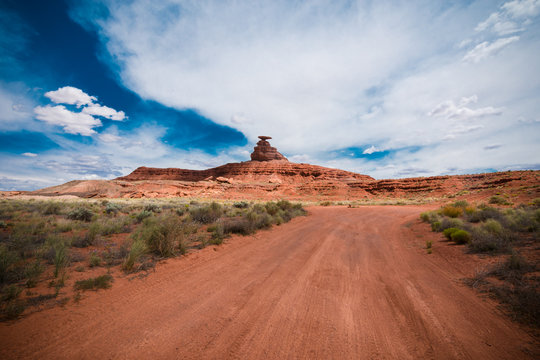 Dirt Road Trail Leads To The Mexican Hat Rock Formation In The Utah Desert. Wide Angle