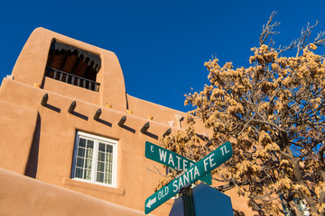 Fototapeta premium Znak ulicy dla historycznego Starego Szlaku Santa Fe i budynku adobe w stylu pueblo w Santa Fe w Nowym Meksyku