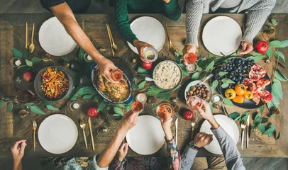 Foto op Plexiglas Traditioneel kerstfeest, nieuwjaarsfeest. Flat-lay van vrienden of familie feesten aan feestelijke tafel met kalkoen of kip, geroosterde groenten, champignonsaus en fruit, bovenaanzicht © sonyakamoz