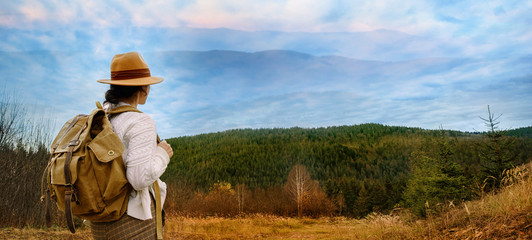 Woman traveler with backpack enjoying sunset on peak of  mountain.  Concept of travel.
