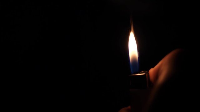 Flaming lighter in hands in the dark