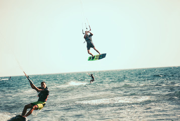 Professional kiter makes the difficult trick on a beautiful background. Kitesurfing Kiteboarding action photos man among waves quickly goes