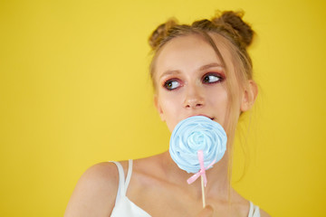 young girl with candy on a yellow bright background. beautiful make-up,