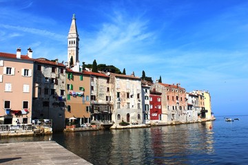 Fototapeta premium Croatia, Rovinj, August 2018: Adriatic, streets of a small seaside town, sunny hot summer day, old weathered houses, windows with multi-colored shutters, drying clothes on ropes, yachts, blue sea.