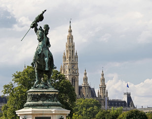 Fototapeta na wymiar Rathaus towers behind a statue