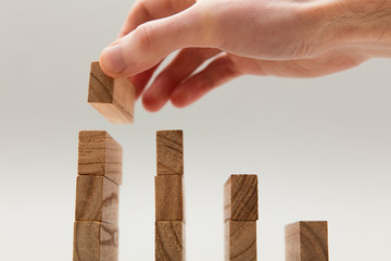 Male hand stacking wooden blocks. Business development and growth concept
