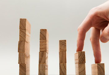 Persons hand walking up a set of wooden blocks. Business development and growth concept