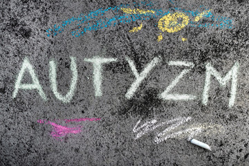 Kolorowy rysunek wykonany kreda na chodniku: Napis AUTYZM
