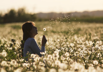 Lady blowing dandelion fluff