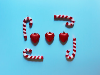 Christmas candy cane and hearts at studio above view over a light blue background isolated flatlay