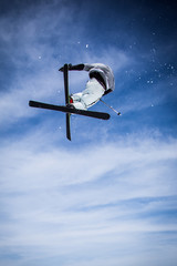 skier jumping in air with blue sky in background.
