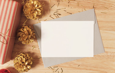 mockup paper card with golden pine cones christmas and gift box decoration on wood table background.