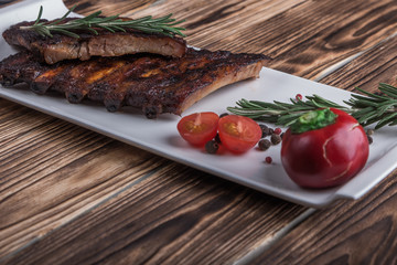 baked ribs on white plate with tomatoes and spices