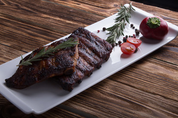 baked ribs on white plate with tomatoes and spices
