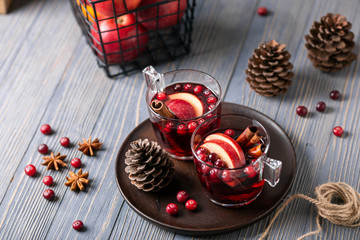 Mulled wine in glasses on a wooden background. Apples, cranberries, cinnamon, star anise, walnuts, cones