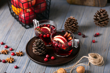 Mulled wine in glasses on a wooden background. Apples, cranberries, cinnamon, star anise, walnuts, cones