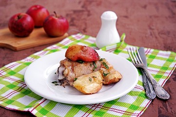 Chicken, baked with apples, on a white plate.