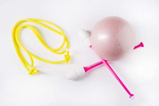Accessories for rhythmic gymnastics ball, clubs, ribbon, rope lie on the floor. White background