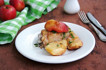 Chicken, baked with apples, on a white plate.