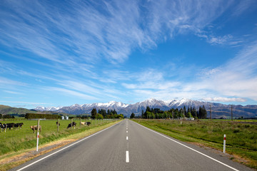 A rural road through farmland and heading towards the mountains with beautiful scenery